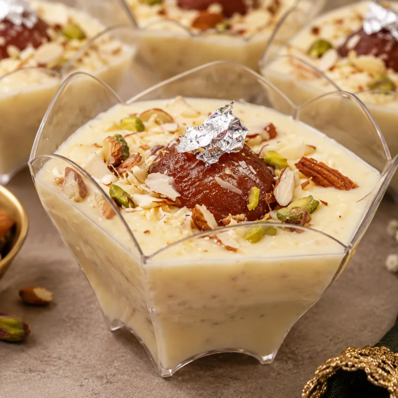 Rabri gulab jamun served in a dessert cup with almonds, pistachios and edible silver leaf